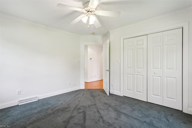 unfurnished bedroom featuring visible vents, crown molding, ceiling fan, baseboards, and dark colored carpet