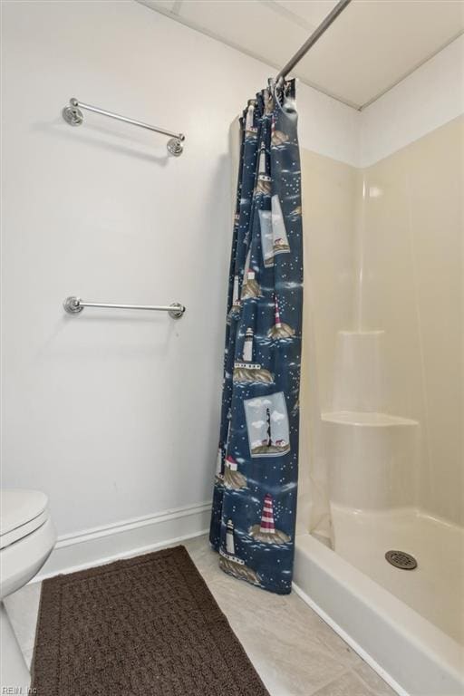 full bathroom with baseboards, toilet, and a shower stall