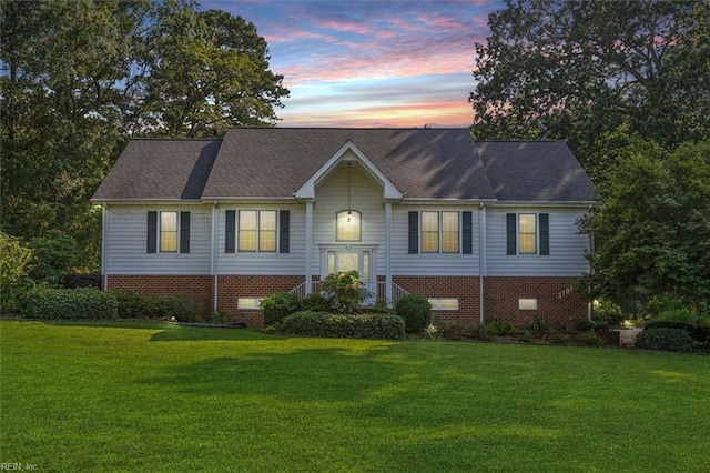 raised ranch featuring brick siding and a front lawn