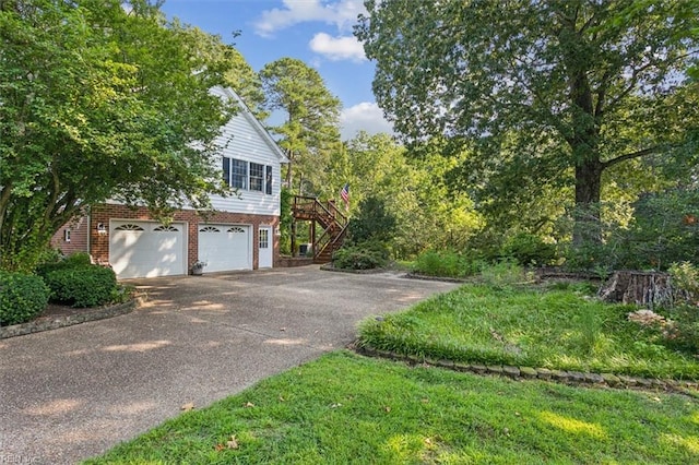 view of home's exterior featuring brick siding, an attached garage, stairs, and aphalt driveway