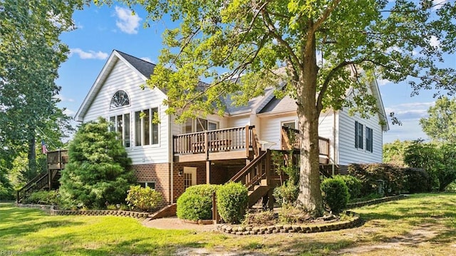 back of property featuring stairway, a yard, brick siding, and a wooden deck