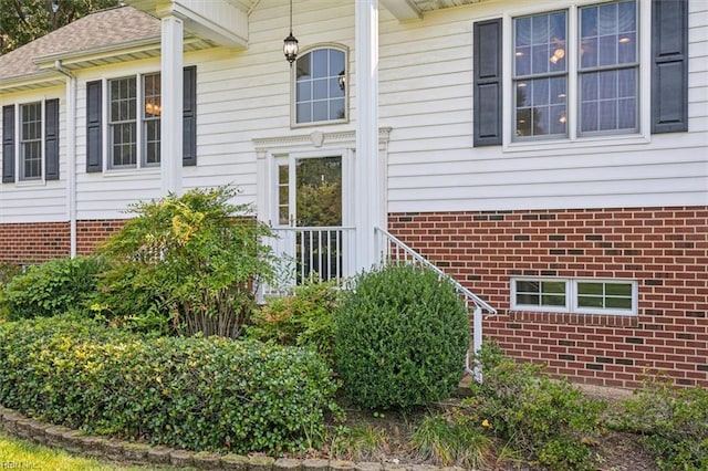 property entrance featuring brick siding and a shingled roof