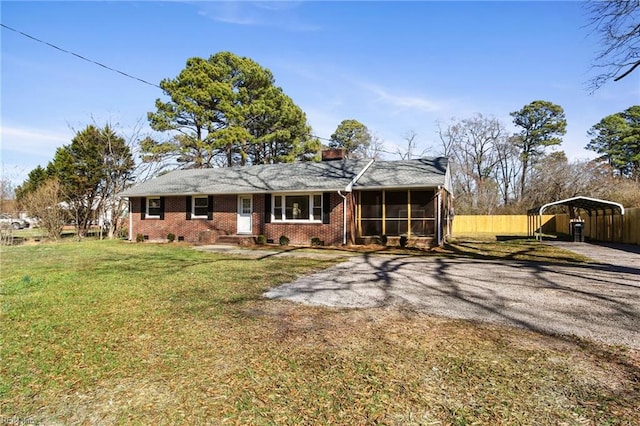 view of front of property with a carport, a sunroom, and a front yard