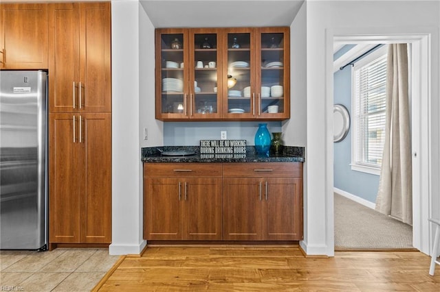 bar featuring baseboards, stainless steel fridge, and light wood-style floors