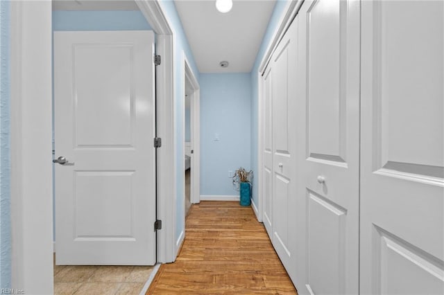 corridor with light wood-type flooring and baseboards