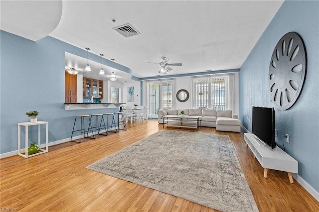 living room with visible vents, ceiling fan, baseboards, and wood finished floors