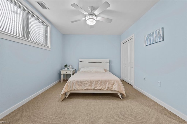 bedroom with baseboards, visible vents, a ceiling fan, light colored carpet, and a closet