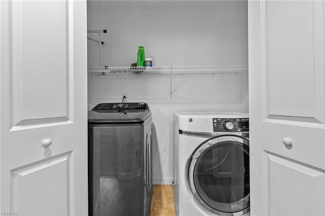 clothes washing area featuring laundry area, washing machine and clothes dryer, and light tile patterned floors