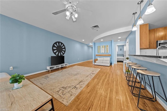 living area featuring baseboards, visible vents, ceiling fan, light wood-type flooring, and recessed lighting