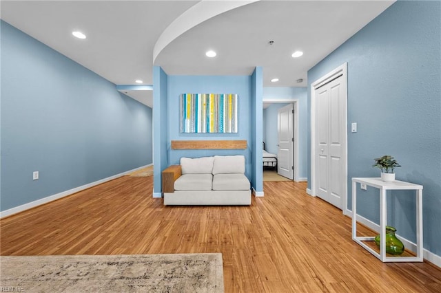 sitting room featuring arched walkways, recessed lighting, baseboards, and wood finished floors