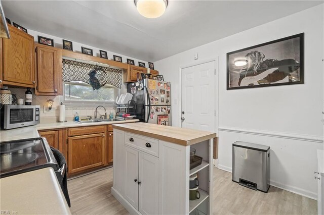 kitchen featuring light hardwood / wood-style flooring, butcher block countertops, stainless steel appliances, sink, and decorative backsplash