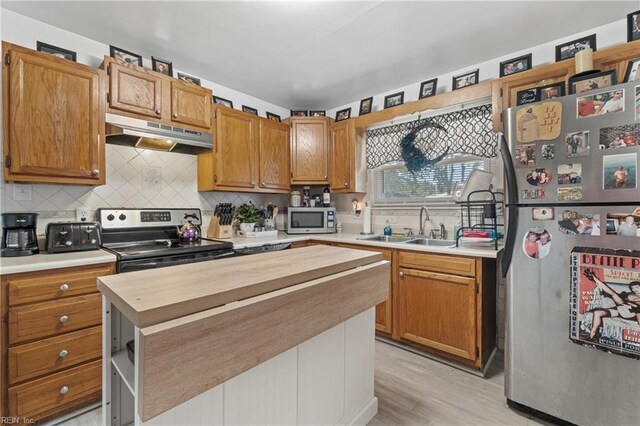 kitchen featuring butcher block countertops, stainless steel appliances, sink, decorative backsplash, and light hardwood / wood-style floors