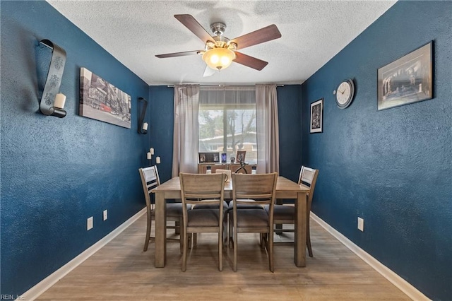 dining room with ceiling fan, hardwood / wood-style flooring, and a textured ceiling