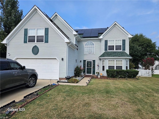 traditional home with a garage, driveway, fence, roof mounted solar panels, and a front lawn