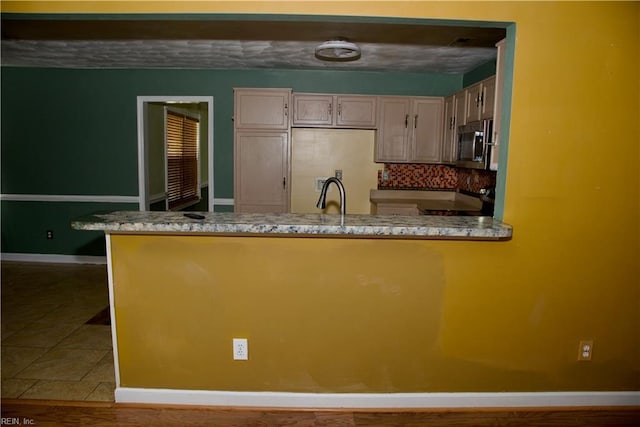 6703 Chambers Ln, Suffolk, VA 23435 - kitchen featuring stove, a peninsula, stainless steel microwave, baseboards, and backsplash