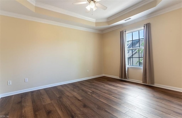 spare room with dark wood-style flooring, visible vents, baseboards, ornamental molding, and a tray ceiling