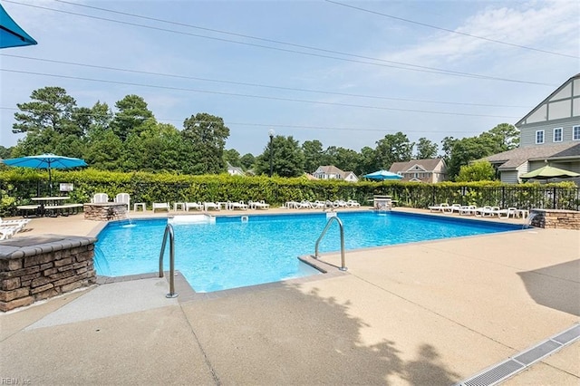 community pool with a patio area and fence