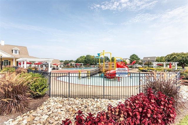 view of jungle gym with a community pool, fence, and a water play area