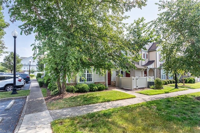 view of front of house with uncovered parking, a front yard, and fence