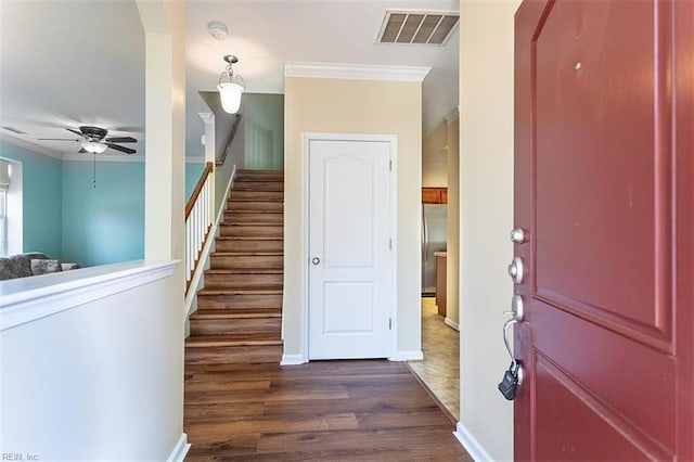 foyer with dark wood-type flooring, visible vents, crown molding, and stairway