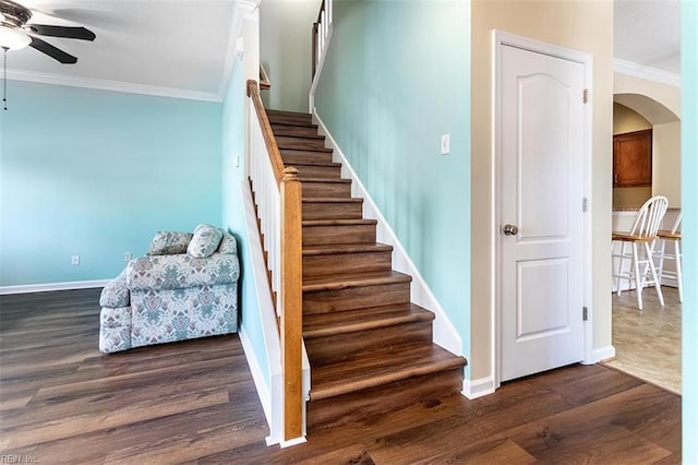 stairs with ornamental molding, arched walkways, ceiling fan, and wood finished floors