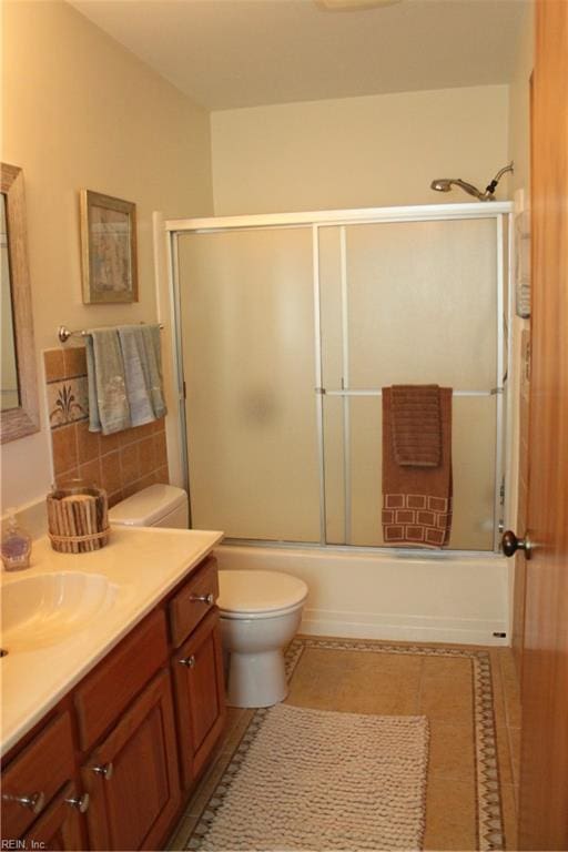 full bathroom featuring enclosed tub / shower combo, tile patterned flooring, tile walls, vanity, and toilet