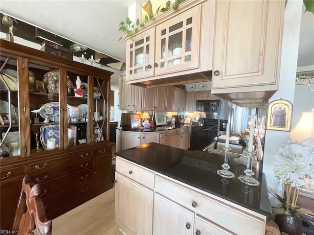 kitchen with light hardwood / wood-style flooring, cream cabinetry, and black appliances