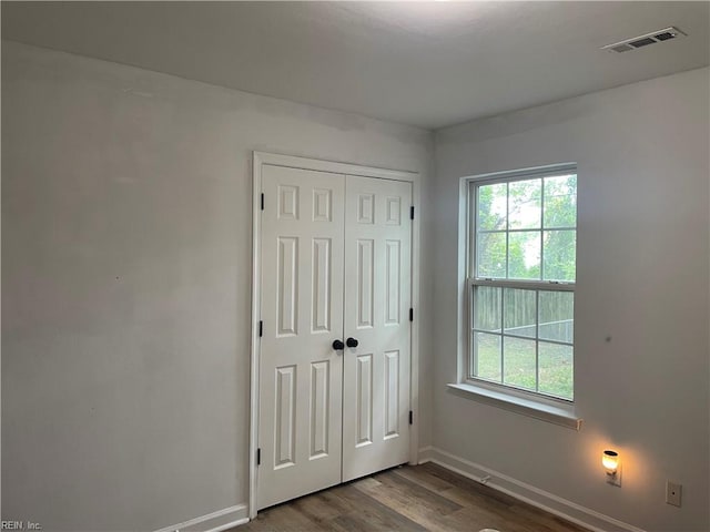 unfurnished bedroom featuring multiple windows, wood-type flooring, and a closet