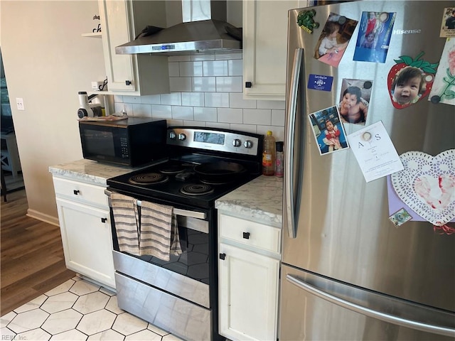 kitchen with light wood-type flooring, white cabinetry, stainless steel appliances, decorative backsplash, and wall chimney exhaust hood