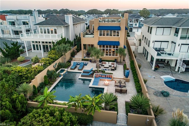 pool at dusk with outdoor lounge area and a patio