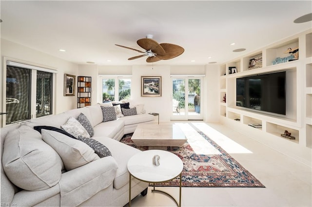 living room with built in shelves, ceiling fan, and a wealth of natural light