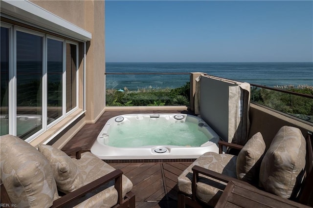 balcony featuring an outdoor hot tub and a water view