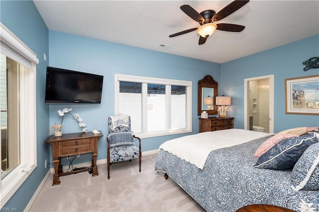 bedroom with ceiling fan, light carpet, and ensuite bath