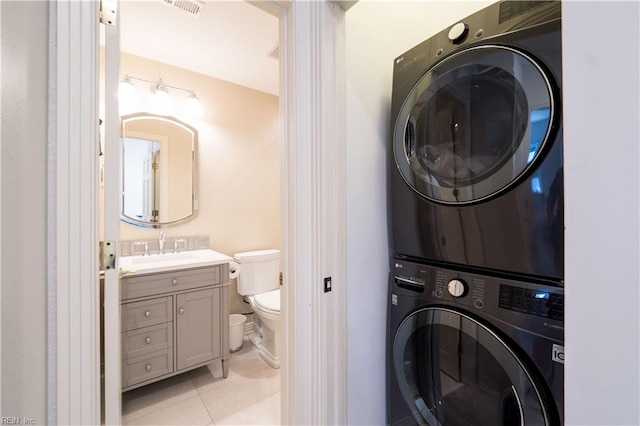 clothes washing area featuring light tile patterned floors, sink, and stacked washer / drying machine