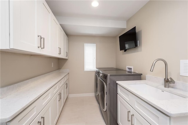 laundry area featuring cabinets, washer and clothes dryer, and sink