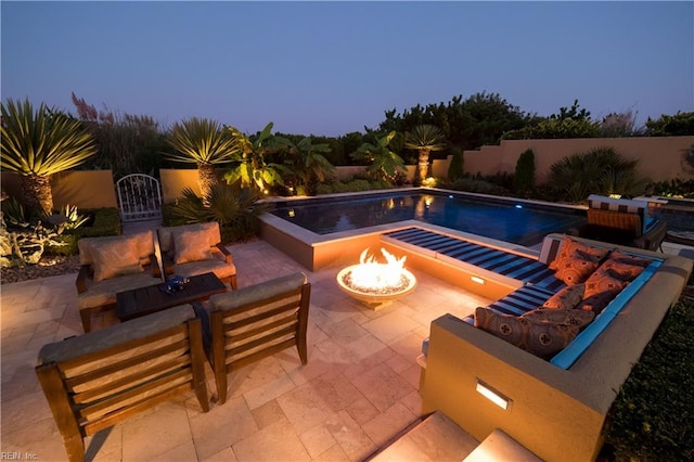 pool at dusk featuring a fire pit and a patio