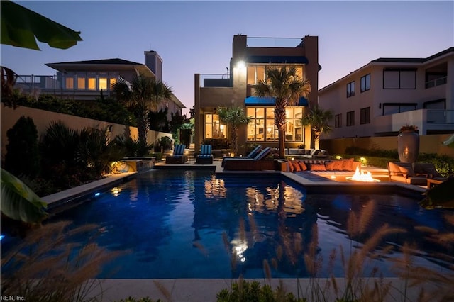 pool at dusk with a patio and an outdoor fire pit