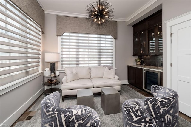 living room featuring crown molding, wine cooler, indoor wet bar, and a chandelier