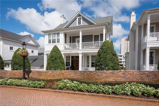 view of front of home featuring a chimney and a balcony