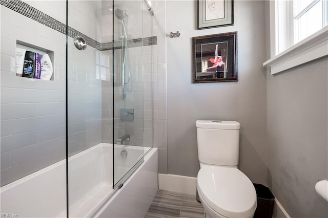 bathroom with toilet and combined bath / shower with glass door