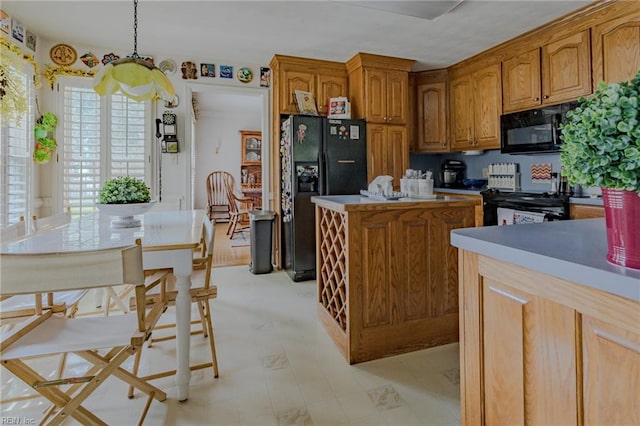 kitchen with brown cabinets, black appliances, a center island, light countertops, and hanging light fixtures