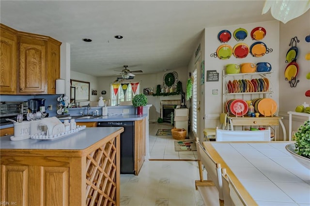 kitchen featuring brown cabinets, a ceiling fan, a sink, a peninsula, and dishwasher