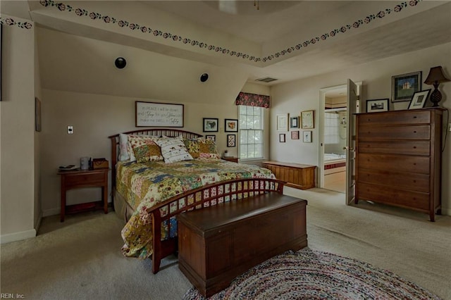 bedroom featuring visible vents, baseboards, carpet floors, ensuite bath, and a raised ceiling