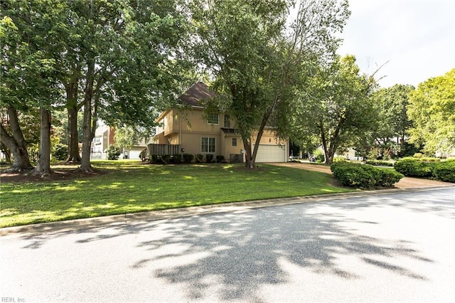 view of side of property with a lawn, an attached garage, driveway, and stucco siding