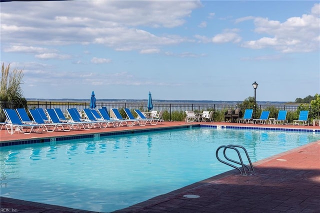 community pool with a patio area and fence