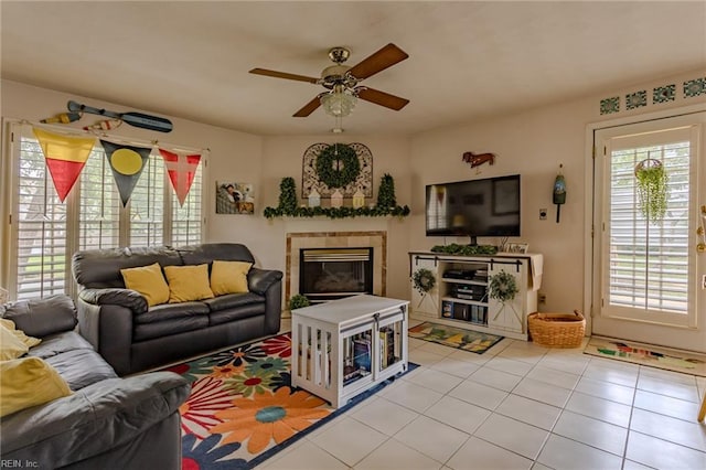 tiled living room with a wealth of natural light, a fireplace, and a ceiling fan