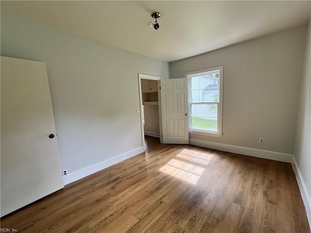 unfurnished bedroom featuring hardwood / wood-style flooring, a walk in closet, and a closet