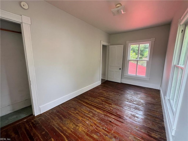 unfurnished bedroom with a closet and dark hardwood / wood-style floors