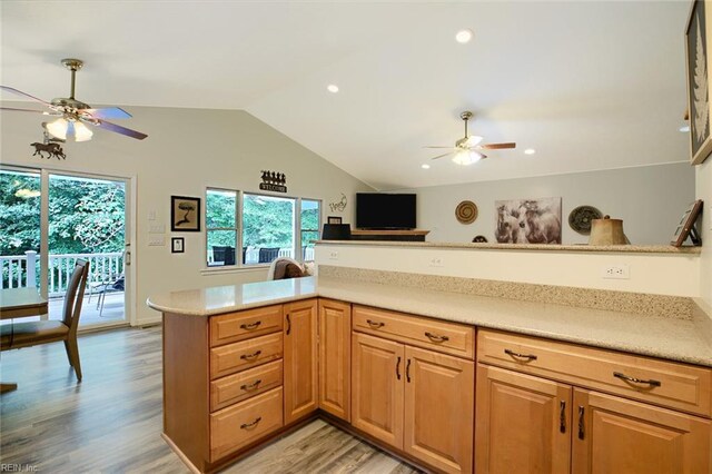 kitchen featuring white appliances, kitchen peninsula, light stone countertops, ceiling fan, and light hardwood / wood-style floors