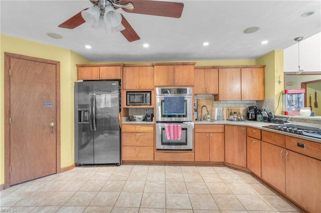 kitchen featuring light tile patterned floors, stainless steel appliances, sink, ceiling fan, and decorative backsplash